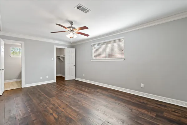 an empty room with wooden floor ceiling fan and windows