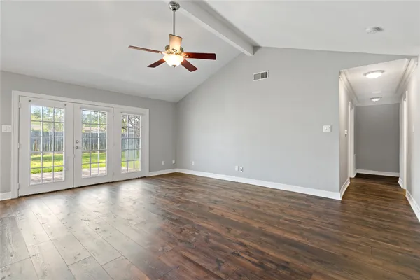 a view of an empty room with wooden floor and a window