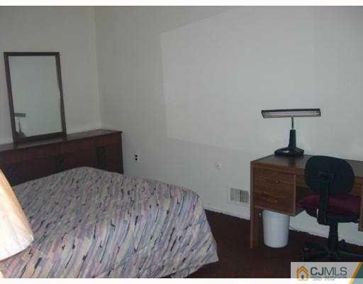 33 Meredith Road Piscataway, NJ 08854 - Photo 7 of 8 a bed sitting in a bedroom next to a lamp and dresser