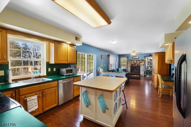 a kitchen with stainless steel appliances granite countertop a refrigerator a stove top oven a sink dishwasher and dining table with wooden floor