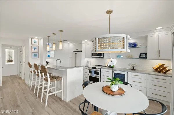 a kitchen with granite countertop stainless steel appliances a dining table and chairs