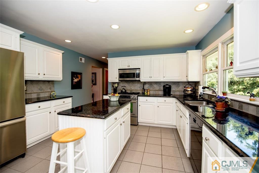 91 Conover Road West Windsor, NJ 08550 - Photo 6 of 25 a kitchen with granite countertop a sink stainless steel appliances and white cabinets