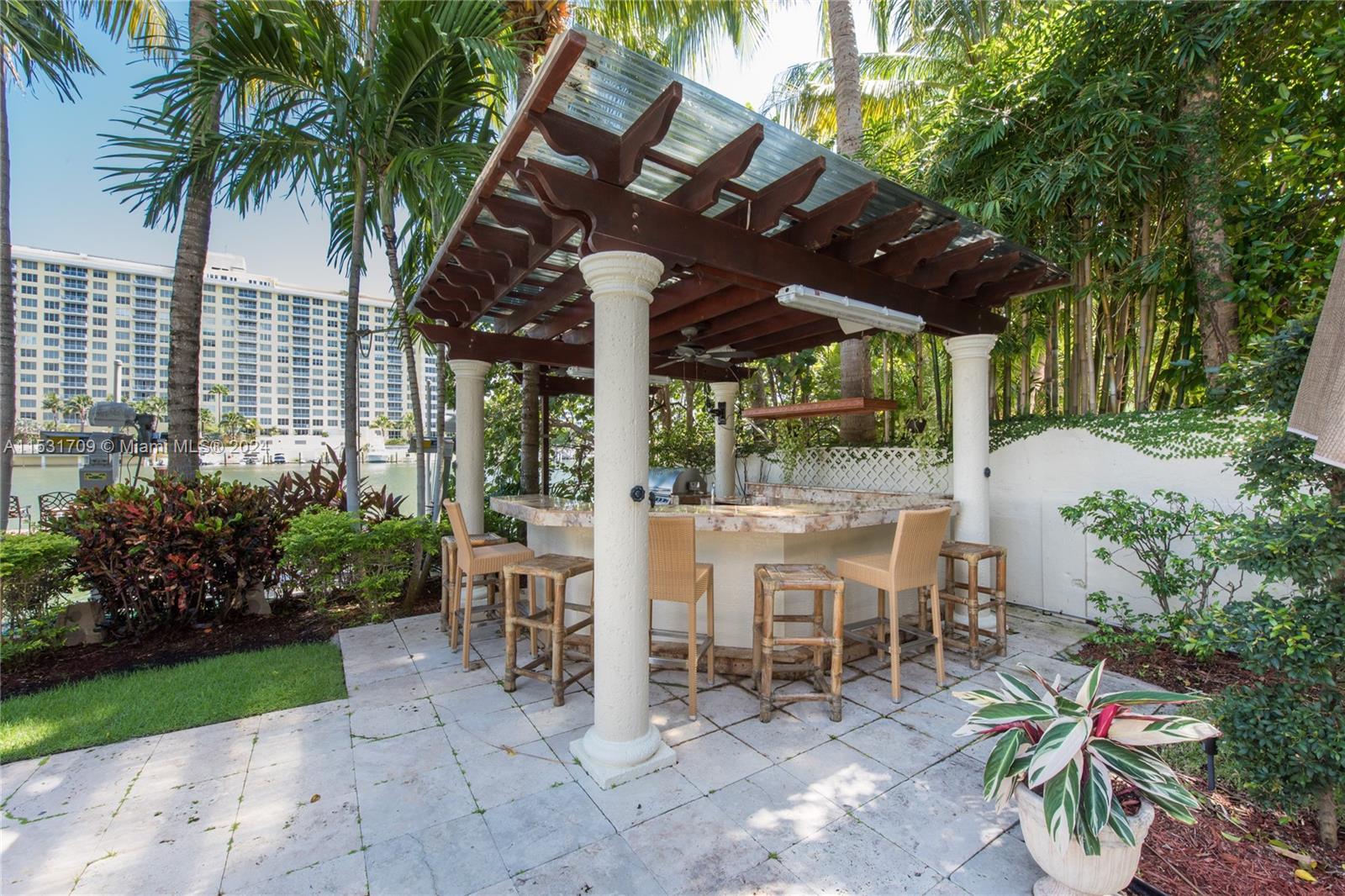 5655 Pine Tree Drive Miami Beach, FL 33140 - Photo 13 of 21 a view of a patio with table and chairs potted plants and large tree
