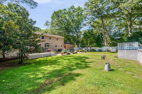 a view of a white house with a small yard and sitting area