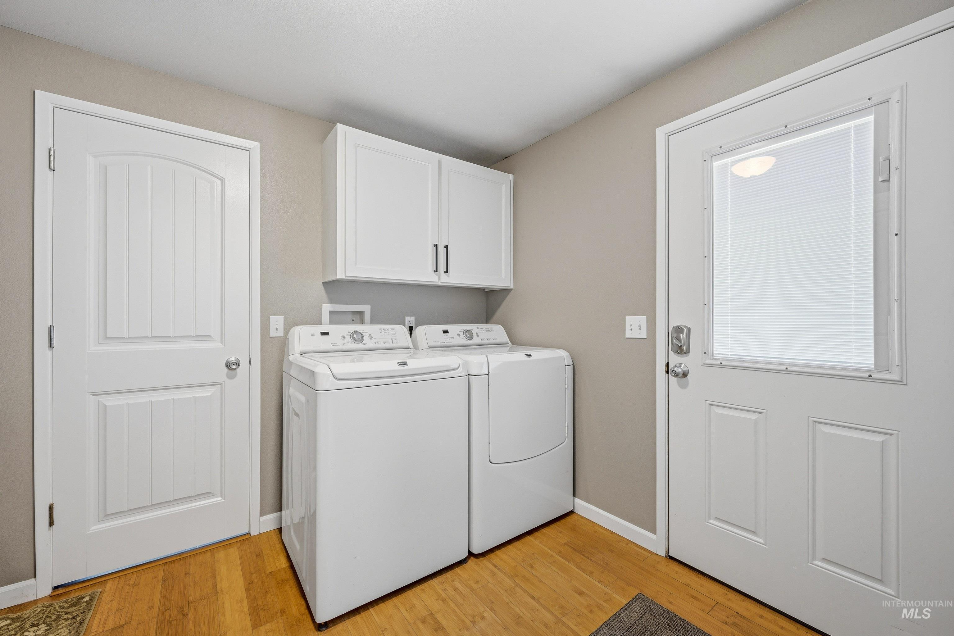 3715 18th Street Lewiston, ID 83501 - Photo 21 of 30 Dedicated laundry area featuring wood-finish flooring, white wall-mounted cabinetry with dark hardware, and a door with an integrated window blind
