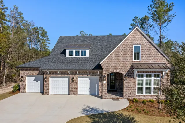 a front view of a house with yard and trees in the background