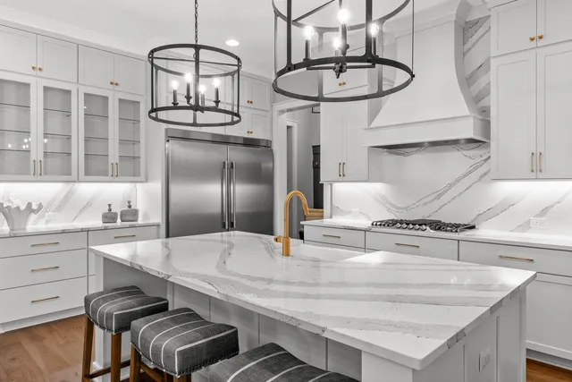 a kitchen with stainless steel appliances kitchen island a table chairs in it and wooden floors