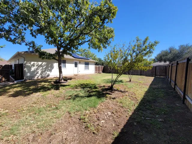 a view of a yard with wooden fence