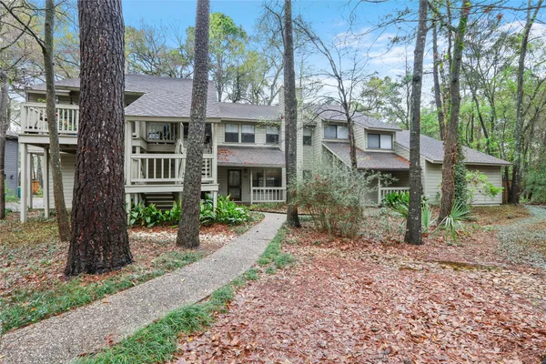 a view of a brick house next to a yard with large trees
