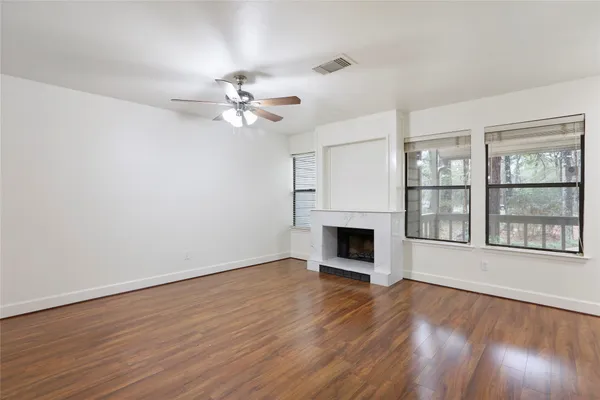 a view of an empty room with wooden floor fireplace and a window