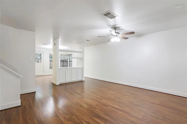 a view of an empty room with window and wooden floor