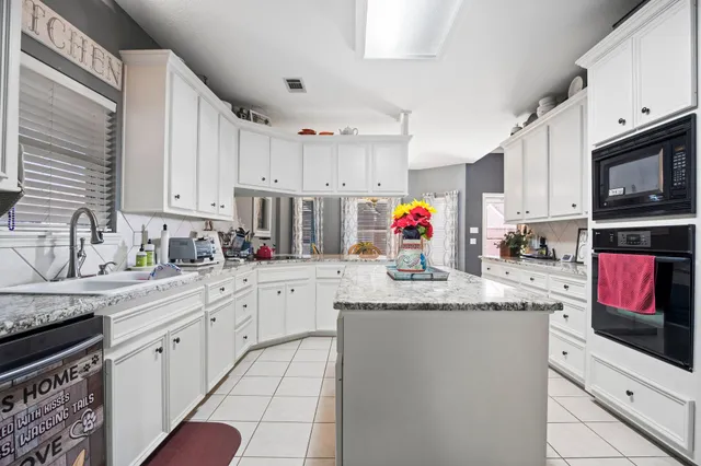 a kitchen with granite countertop a sink stainless steel appliances and white cabinets