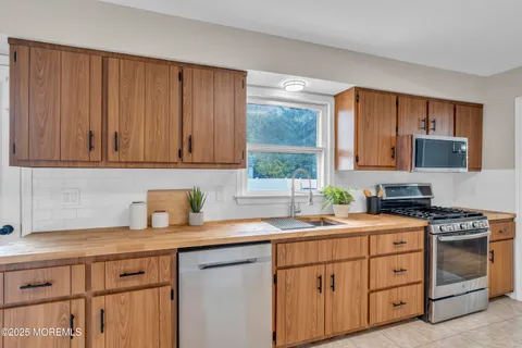 a kitchen with stainless steel appliances granite countertop a sink a stove a microwave cabinets and a window