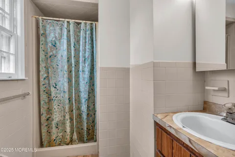 a bathroom with a granite countertop sink a mirror and shower