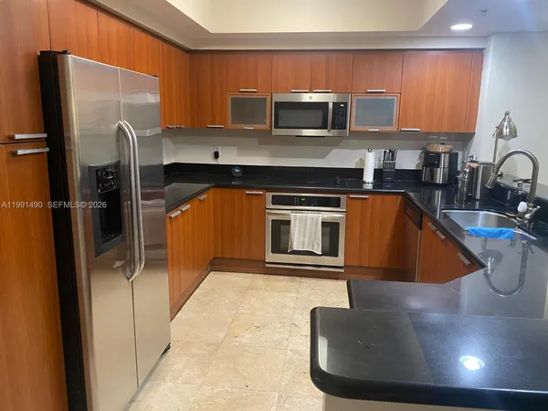 a kitchen with stainless steel appliances granite countertop a sink and a refrigerator