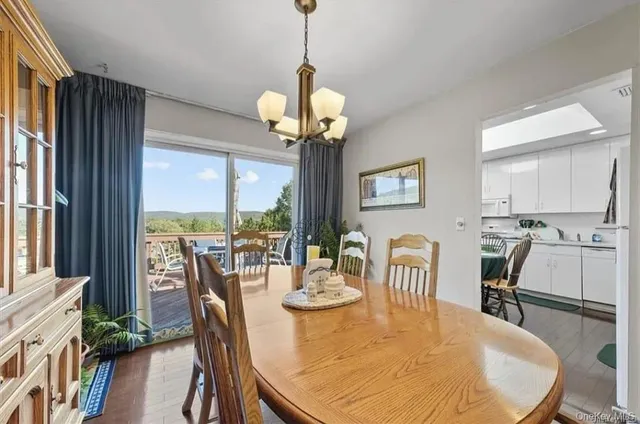 a view of a dining room with furniture a chandelier and large windows