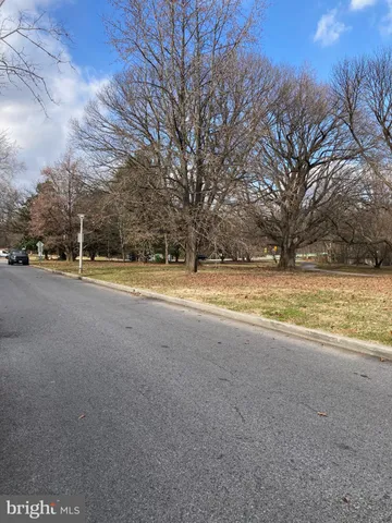 a view of a house with a yard and a large tree