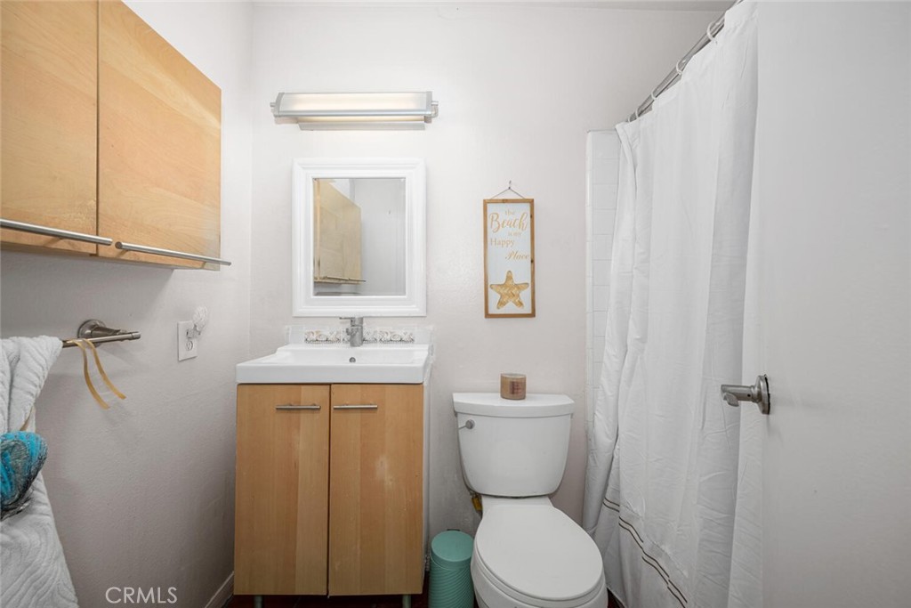 16393 Del Oro Circle, Unit 123 Huntington Beach, CA 92649 - Photo 14 of 24 a bathroom with a toilet a sink and mirror