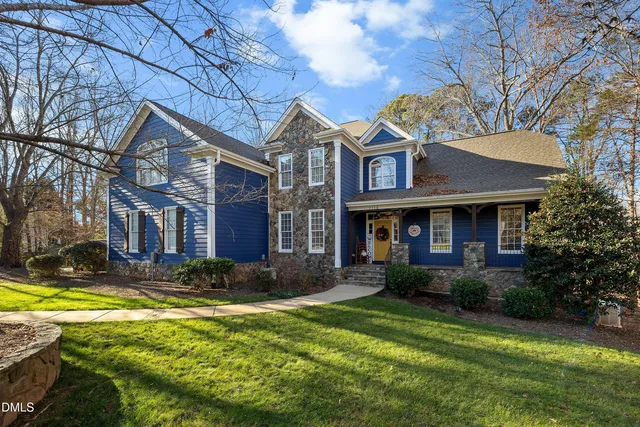 a view of a brick house with a yard patio and a tree