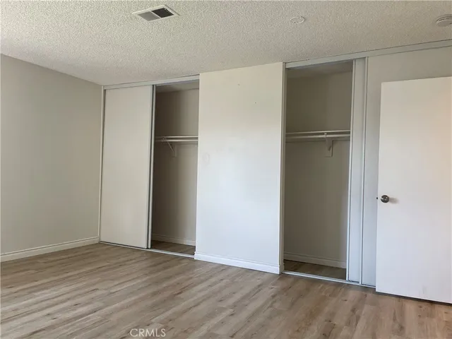 a view of an empty room with wooden floor and closet area