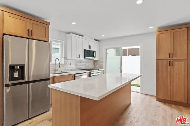 a large kitchen with stainless steel appliances a refrigerator and a stove top oven