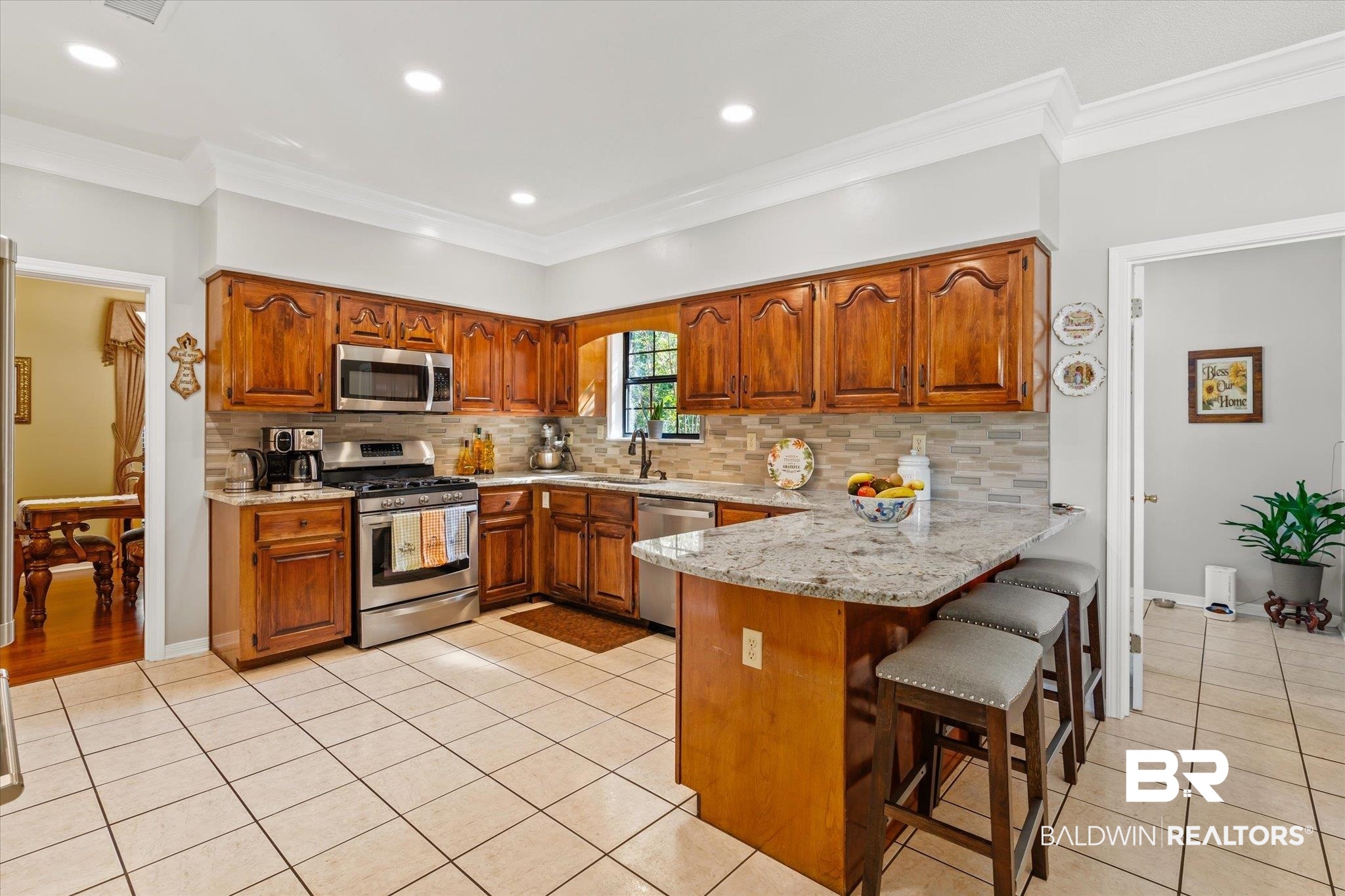 7360 Bridgewood Court Mobile, AL 36695 - Photo 9 of 30 Kitchen with a breakfast bar, sink, ornamental molding, appliances with stainless steel finishes, and light tile patterned floors