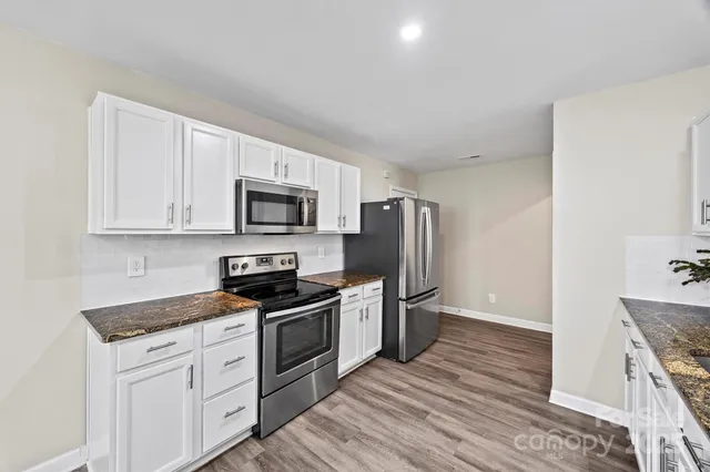 a kitchen with granite countertop a refrigerator stove and microwave
