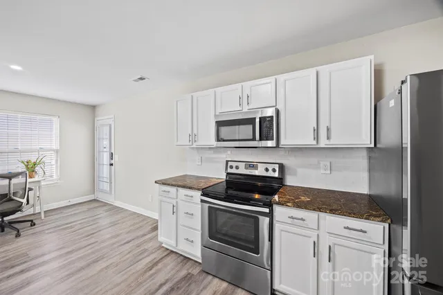 a kitchen with granite countertop a stove a sink and a refrigerator