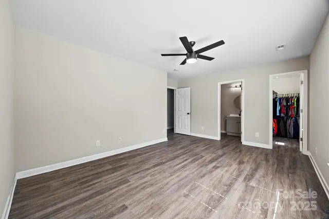 a view of empty room with wooden floor and ceiling fan