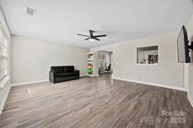 an empty room with wooden floor a ceiling fan and windows