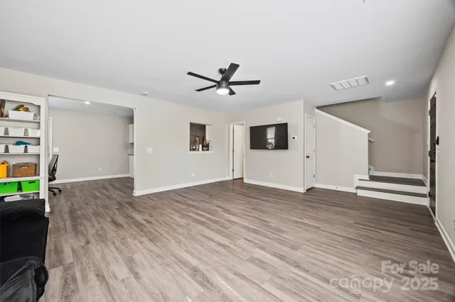 a view of a livingroom with a ceiling fan wooden floor and a ceiling fan