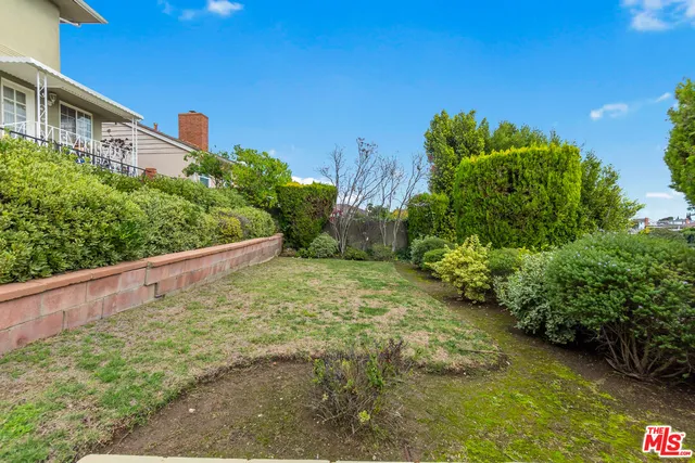 a view of a yard with plants and wooden fence