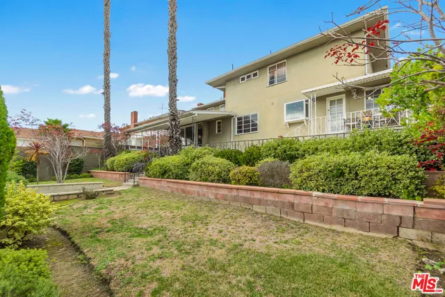 a view of a white house with a large windows and plants