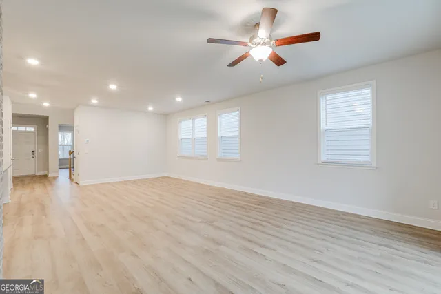 an empty room with wooden floor and windows
