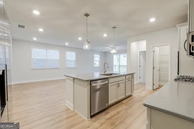 a large kitchen with stainless steel appliances granite countertop a sink a stove and a wooden floors