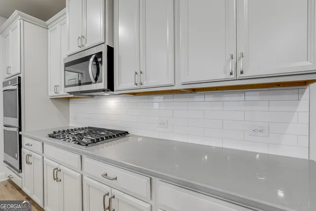 a kitchen with white cabinets and appliances