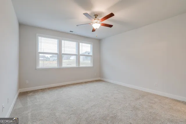 an empty room with ceiling fan and window