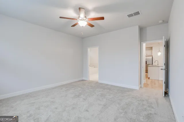 an empty room with a ceiling fan and a view of a bathroom