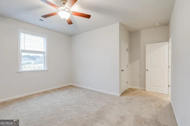 an empty room with a window and a ceiling fan