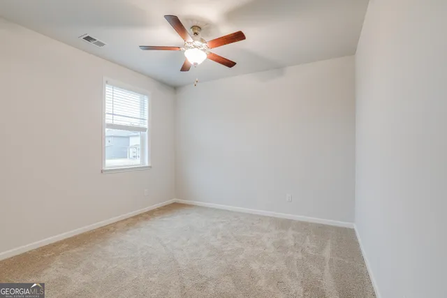 an empty room with ceiling fan and window