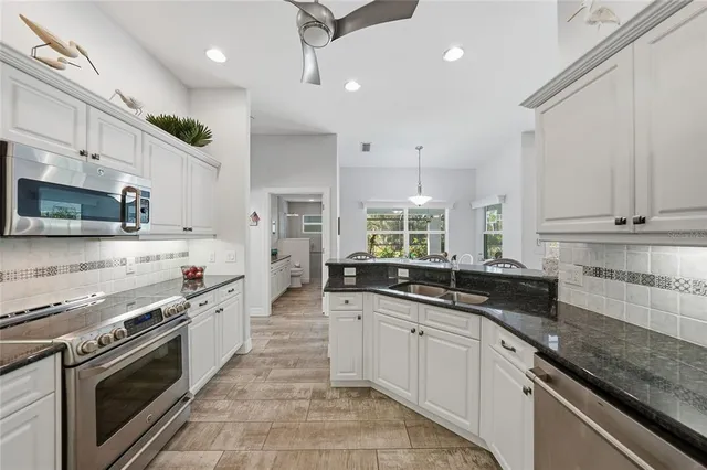 a large kitchen with stainless steel appliances granite countertop a sink a stove and cabinets