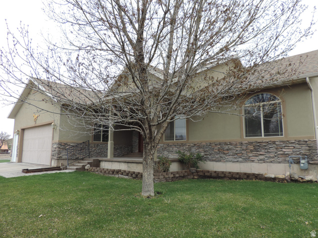View of side of home featuring stone siding, a yard, and stucco siding