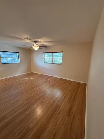 an empty room with wooden floor and windows