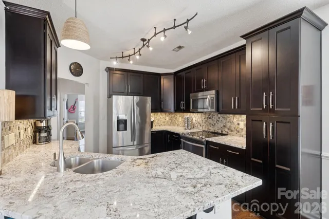 a kitchen with stainless steel appliances kitchen island granite countertop a sink refrigerator and cabinets