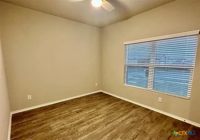 a view of an empty room with a window and wooden floor