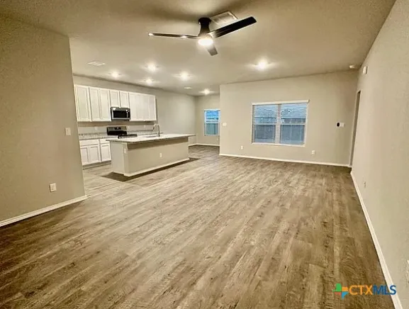 a large white kitchen with kitchen island a sink dishwasher a stove and a refrigerator with wooden floor