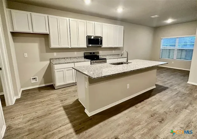 a kitchen with stainless steel appliances granite countertop a sink stove and cabinets