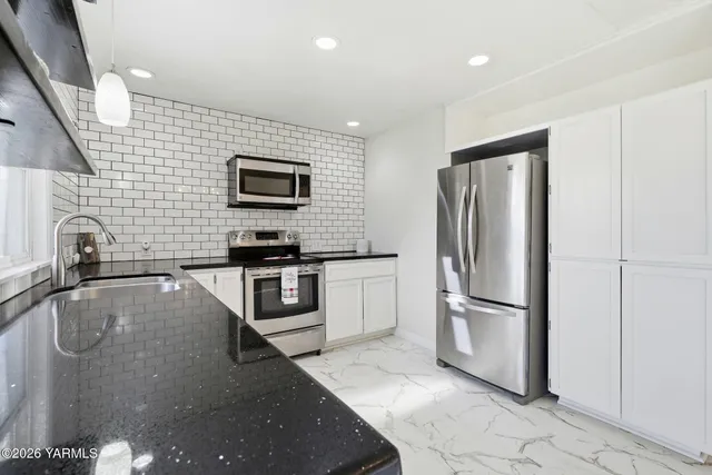 a kitchen with granite countertop a refrigerator and a sink