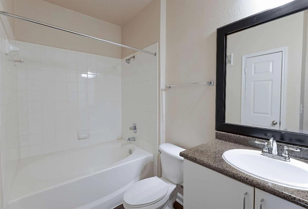 10505 I-35 Frontage Road South, Unit 2432 Austin, TX 78747 - Photo 17 of 22 a bathroom with a granite countertop sink mirror toilet and bathtub
