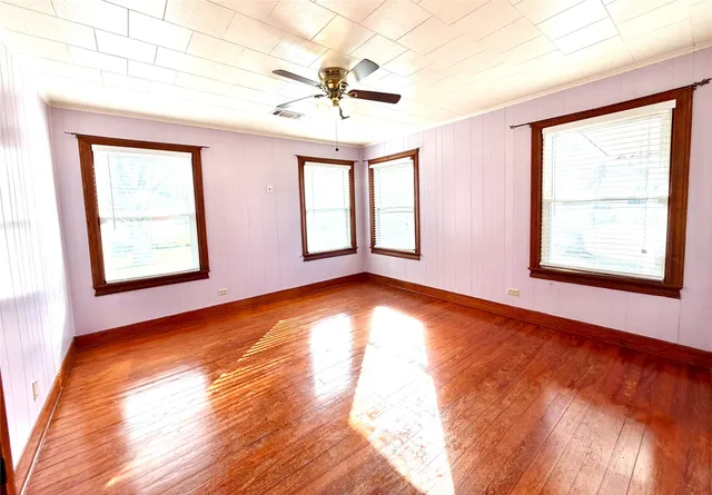 a view of an empty room with window and wooden floor